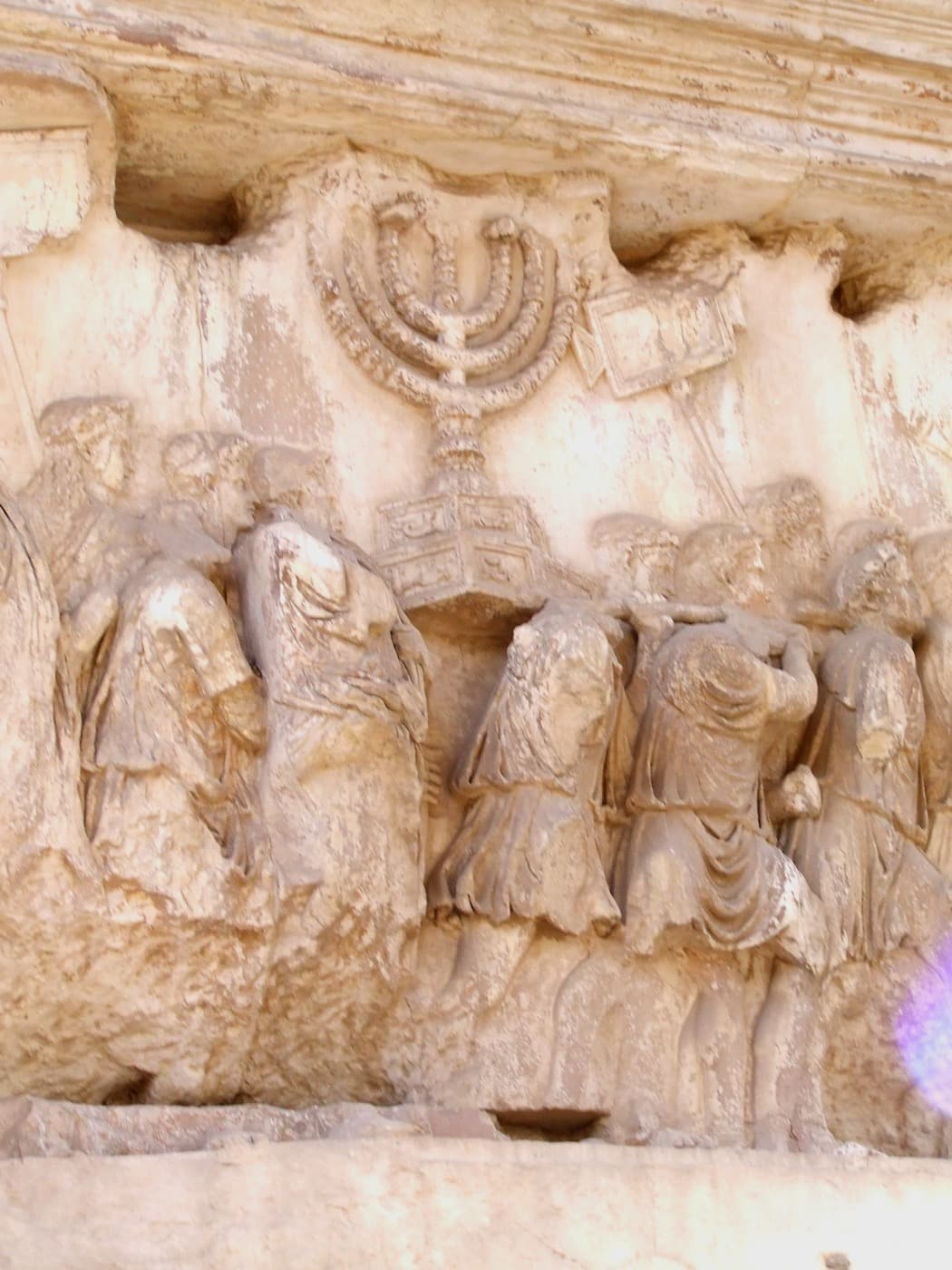 A marble relief of Roman soldiers carrying a large seven-branched lampstand and other objects in a procession